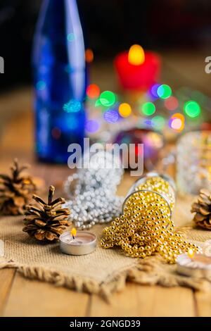 Two champagne glasses with Christmas beads. Christmas decorations in rustic style on bright background with lights. Pine cones and burning candles on Stock Photo