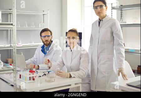 Group portrait of serious young scientists in lab coats and goggles in their laboratory Stock Photo