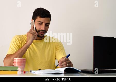 Man talking on the phone. businessman with smartphone in a hotel room. Pleasant conversation. Charming young man sitting at the table and talking on t Stock Photo