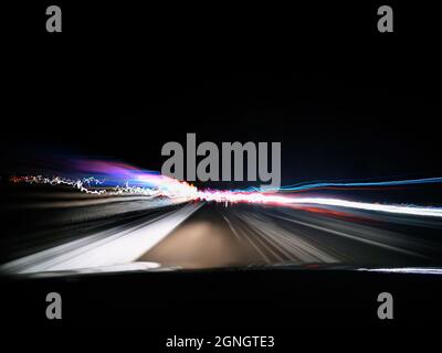 View of night highway neon lights on long exposure from car's front window near a city Stock Photo