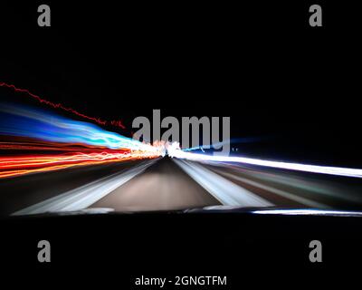 View of night highway neon lights on long exposure from car's front window near a city Stock Photo