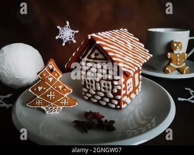 Gingerbread house and christmas tree decorated with white glaze in New Year patterns served with three anise stars Stock Photo