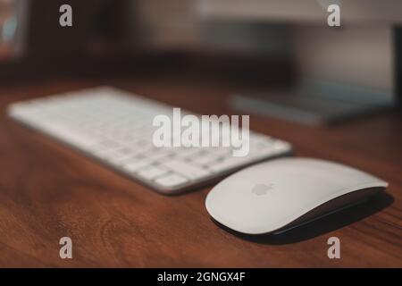 London, UK - May 25, 2021: New Apple Magic Mouse compatible with M1 chip Apple devices on a desk at home. Large number of people continue to work from Stock Photo