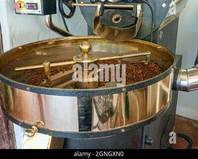 Small, traditional brass coffee bean roaster. The coffee beans can be seen. Stock Photo