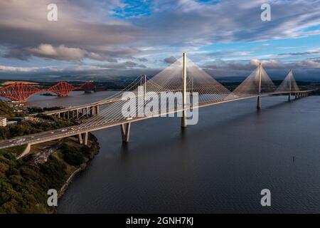 North Queensferry, Eaglesham, Scotland, UK. 25th Sep, 2021. PICTURED: Aerial drone view of Forth bridges. Spanning three centuries in bridge design and connecting two of Scotland's counties of Fife and Lothian, the Queensferry Crossing Scotland's newest bridge designed to look like sails on a ship, connects North Queensferry to South Queensferry, with Forth Road Bridge behind showcasing mid 20th century technology and background Forth Rail Bridge late 1800s with its cantilever construction. Credit: Colin Fisher/Alamy Live News