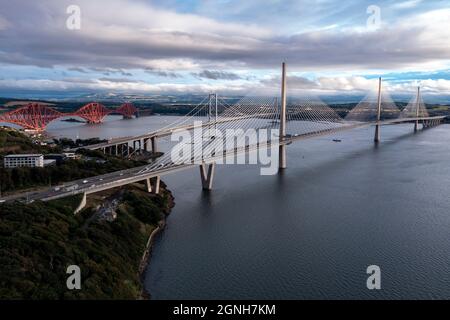 North Queensferry, Eaglesham, Scotland, UK. 25th Sep, 2021. PICTURED: Aerial drone view of Forth bridges. Spanning three centuries in bridge design and connecting two of Scotland's counties of Fife and Lothian, the Queensferry Crossing Scotland's newest bridge designed to look like sails on a ship, connects North Queensferry to South Queensferry, with Forth Road Bridge behind showcasing mid 20th century technology and background Forth Rail Bridge late 1800s with its cantilever construction. Credit: Colin Fisher/Alamy Live News
