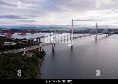 North Queensferry, Eaglesham, Scotland, UK. 25th Sep, 2021. PICTURED: Aerial drone view of Forth bridges. Spanning three centuries in bridge design and connecting two of Scotland's counties of Fife and Lothian, the Queensferry Crossing Scotland's newest bridge designed to look like sails on a ship, connects North Queensferry to South Queensferry, with Forth Road Bridge behind showcasing mid 20th century technology and background Forth Rail Bridge late 1800s with its cantilever construction. Credit: Colin Fisher/Alamy Live News Stock Photo