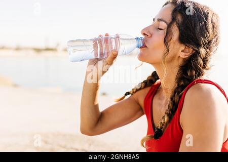 Premium Photo  Fitness young woman drinking water from bottle. muscular  young female at gym taking a break from workout.