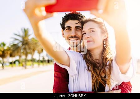 Happy young traveling couple taking selfie portrait with smartphone Stock Photo