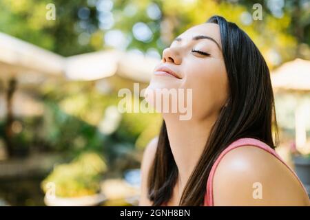 Healthy young adult woman breathing fresh air in the park Stock Photo