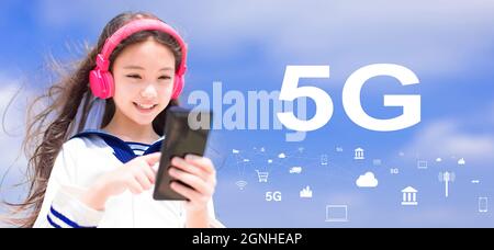 Happy syudent girl  listening music in headphones and holding mobile phone with 5G network concepts Stock Photo