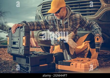 Construction Worker in His 40s and His Tools Boxes in Front of a Pickup Truck. Construction Industry Theme. Stock Photo