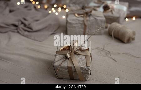 Close-up of a Christmas gift box, decorated with dried flowers and a dry orange, wrapped in craft paper. Stock Photo