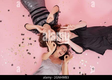 A company of girlfriends is having fun at a Christmas party, lying on a pink background. Stock Photo