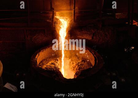 A stream of molten slag is poured into a metallurgical ladle Stock Photo