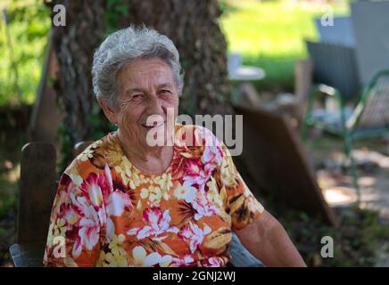 Portrait of senior woman sitting in nature Stock Photo