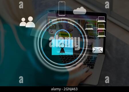 Businesswoman with laptop, desktop at office interior, blue glowing information protection icons. Padlock and business data symbols. Concept of cyber Stock Photo