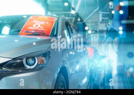 New car parked in luxury showroom with blur electric car charging station for charge electric vehicle battery. EV charger. EV car dealership. Clean Stock Photo