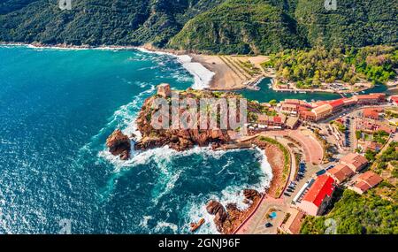 View from flying drone. Incredible summer cityscape of Porto town with Genoise de Porto Ota tower. Aerial morning view of Corsica island, France, Euro Stock Photo