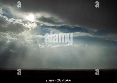 Beautiful sky with storm clouds and sun rays over the plains | Amazing sky over the horizon, with dark grey clouds and sun shining at the same time Stock Photo