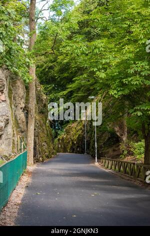 Alingsås, Sweden - August 20 2021: Newly paved path through a small pass between to rock cliffs