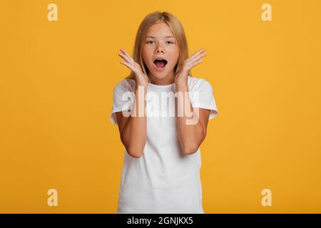 Scared surprised shocked european teenager girl in white t-shirt screaming with open mouth Stock Photo