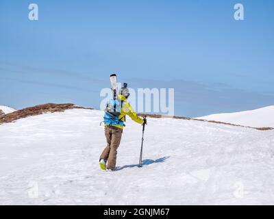 Busteni, Romania - 04.10.2021: Skier in Bucegi Mountains walking on the snow carrying his skis Stock Photo