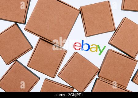 Ebay logo on a white background surrounded by parcel boxes. Stock Photo