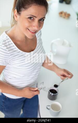 smiling woman adding sugar to her coffee Stock Photo