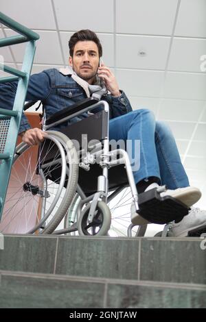 conceptual photo of businessman on wheelchair in front of stairs Stock Photo