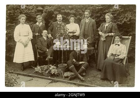 Wonderful original very clear Edwardian real photographic postcard of large Edwardian family group outside in garden on Whit Sunday June 26th 1908, basket of flowers prop, good examples of fashions, men and boy's collars (different styles), women and girl's skirts and blouses, photographer was W.J. Waller, Slinfold, Sussex England, U.K. Stock Photo