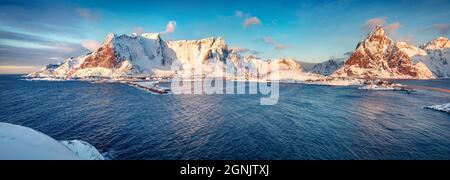 Panoramic morning cityscape of Reine town. Gorgeous view of Lofoten Island with Reinebringen peak on background. Cold winter scene of Norwegian sea. L Stock Photo