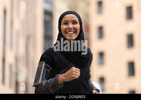 Portrait Of Happy Young Islamic Lady In Hijab Jogging Outdoors Stock Photo