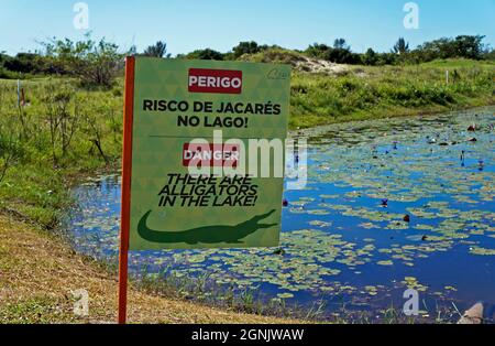 RIO DE JANEIRO, BRAZIL - DECEMBER 16, 2019: Signboard warning the danger of alligators in the lake. Rio Olympic Golf Course in Barra da Tijuca Stock Photo