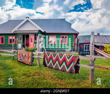 Traditional Carpathian handmade carpets made of goat wool. Old wooden hous in the Snidavka village. Colorful summer view of Carpathian village. Stock Photo