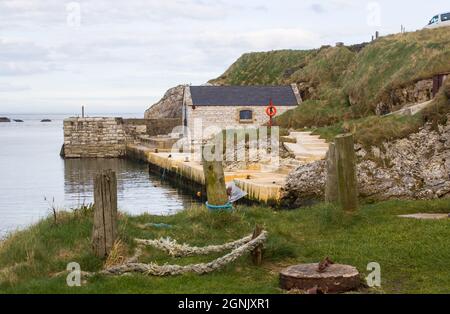 April 2017.The small harbor at Ballintoy on the North Antrim Coast of Northern Ireland with its ancient stone built boathouse on an evening in spring Stock Photo