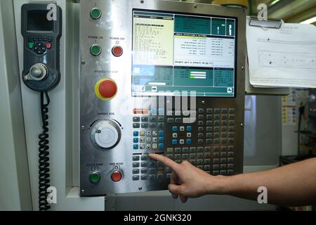Worker hands touching the button on the board of computer numerical control of the CNC milling machine Stock Photo