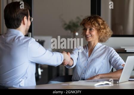 Happy confident young businesswoman shaking hands with client Stock Photo