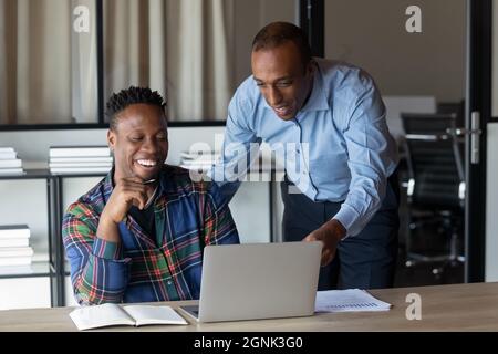Happy African American employees watching video presentation on laptop Stock Photo