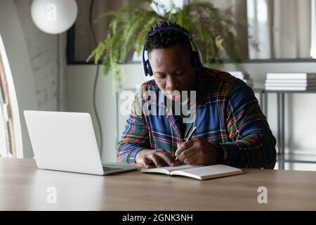 Focused serious African American student guy in headphones watching webinar Stock Photo
