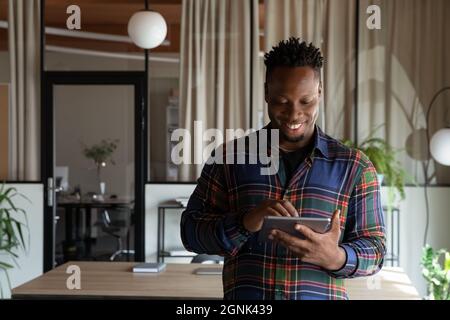 Happy millennial self employed professional using tablet in office Stock Photo