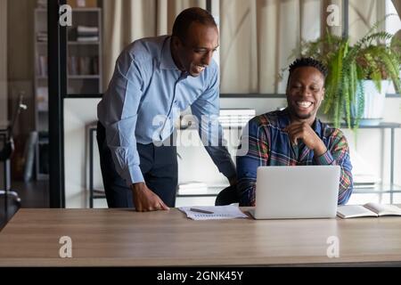 Happy office employees of different ages looking at laptop screen Stock Photo