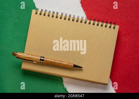 blank notebook against paper abstract in colors of national flag of Italy (green, white and red), Italian American Heritage Month Stock Photo