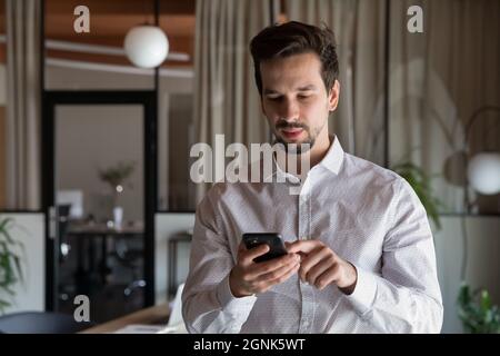Serious millennial businessman texting message on smartphone Stock Photo
