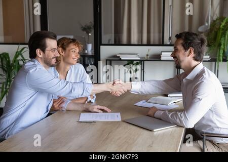 Confident lawyer meeting and shaking hands with happy couple Stock Photo