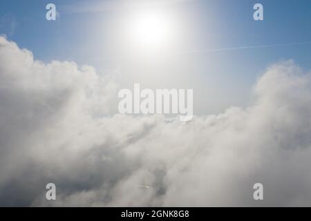 Aerial shot of white fluffy clouds and some blue sky in distance while flying above clouds. Beautiful cumulus clouds captured by a drone. Aerial backg Stock Photo