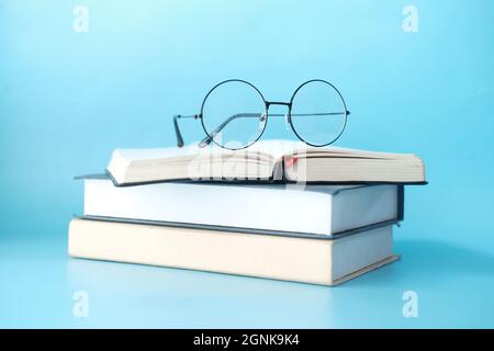 stack of books and eyeglass on blue background  Stock Photo
