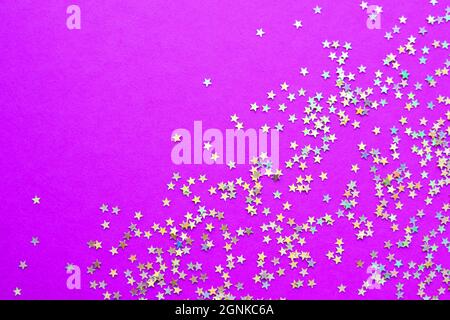 Background of shiny little stars on a bright  pink background. Selective focus. Christmas concept. Glitter texture. Stock Photo