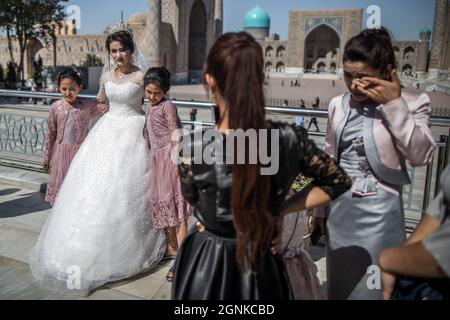 26 September 2021, Uzbekistan, Samarkand: An Uzbek bride has wedding pictures taken at the historical landmark of Registan in Samarkand. The Registan was a public square and center of ancient Samarkand during the Timurid Empire, used for royal proclamations, heralded by blasts on enormous copper pipes and public executions. Photo: Oliver Weiken/dpa Stock Photo