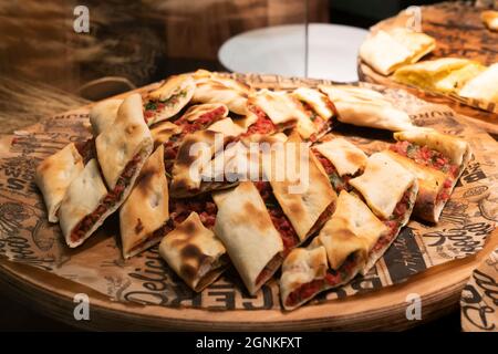pide is a Turkish pizza, cut into pieces on a wooden platter. national Turkish cuisine bakery. Stock Photo
